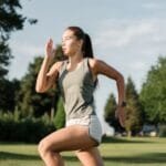 Attractive female runner sprinting on athletic track wearing smartwatch for GPS running and marathon training in India