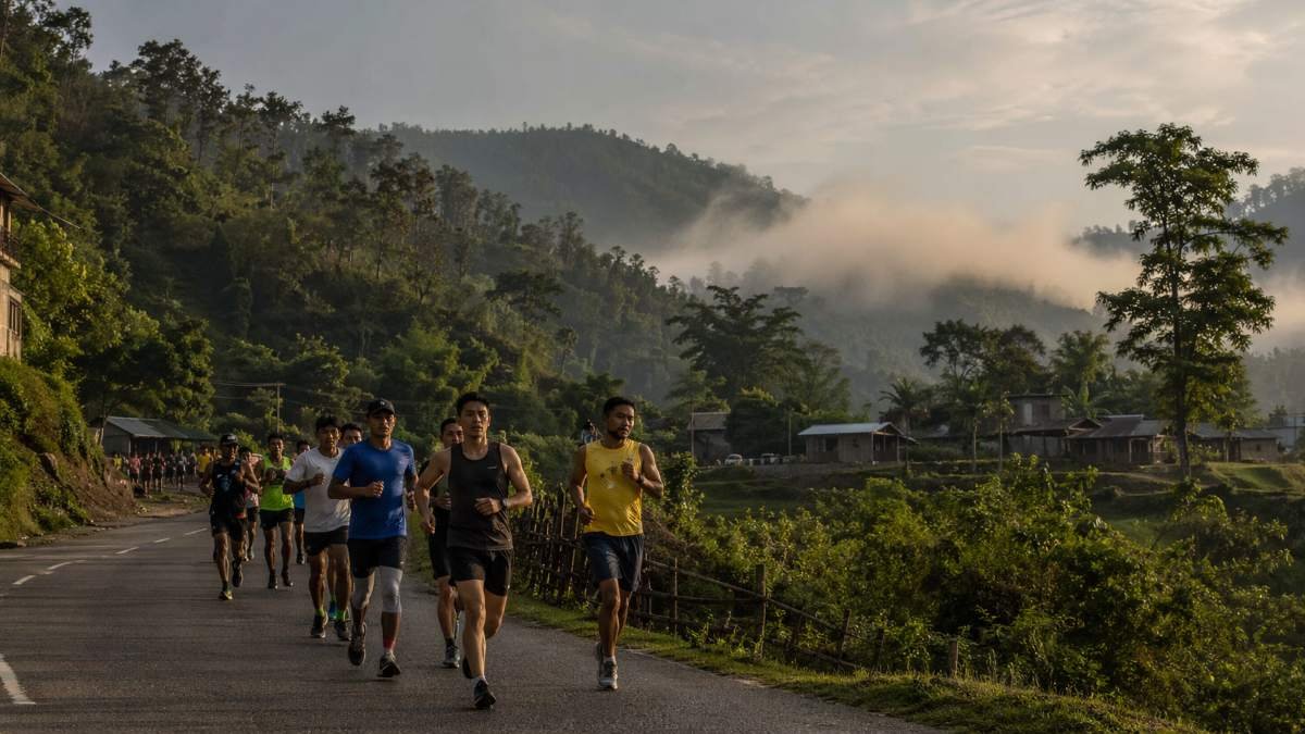 Runners participating in a scenic marathon in Northeast India with lush green hills, misty landscape and rural roads in Assam and Arunachal Pradesh