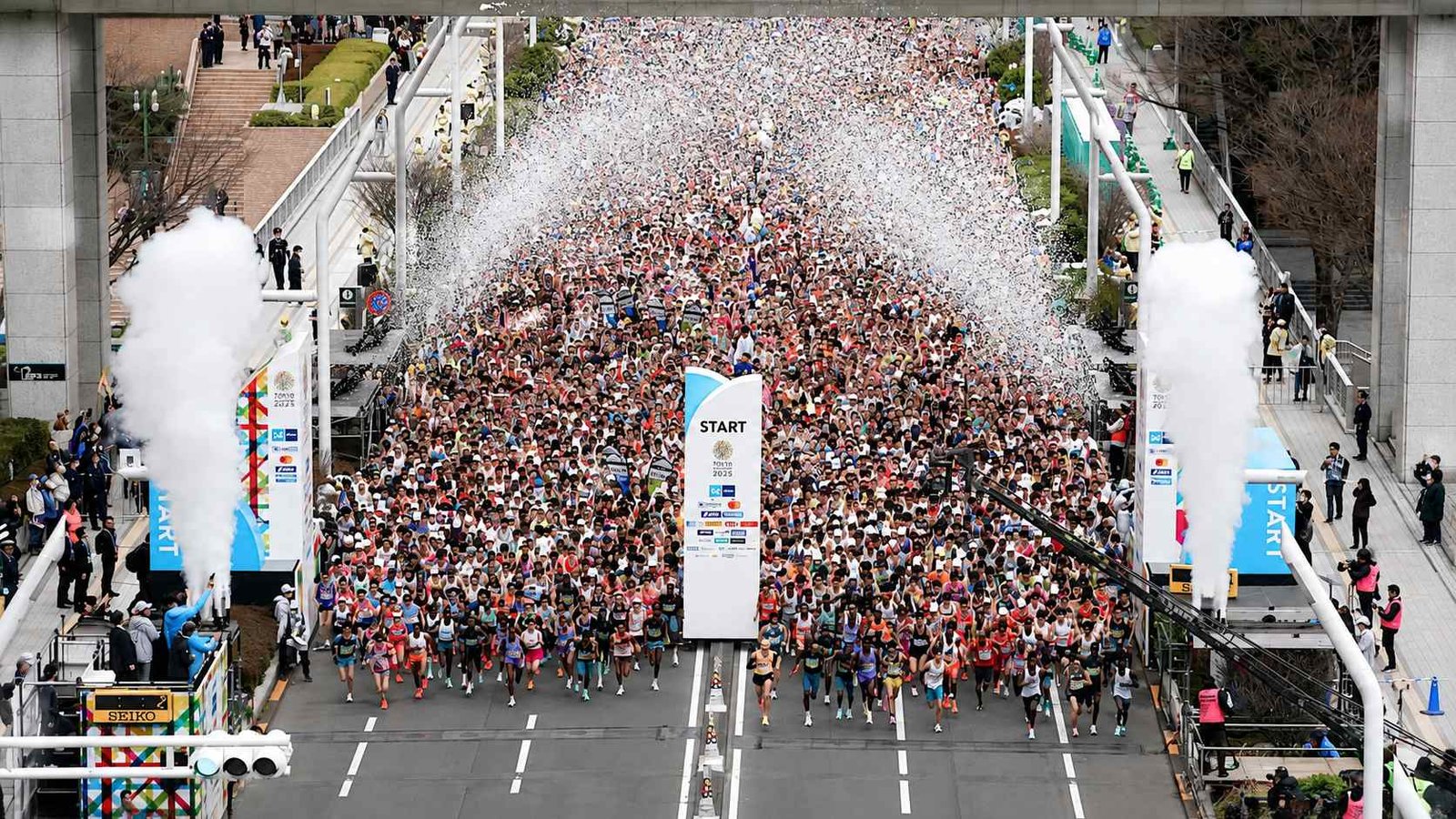 Thousands of runners cross the start line of the Tokyo Marathon 2025 in Tokyo, Japan, as confetti fills the air and race officials oversee the mass participation event.