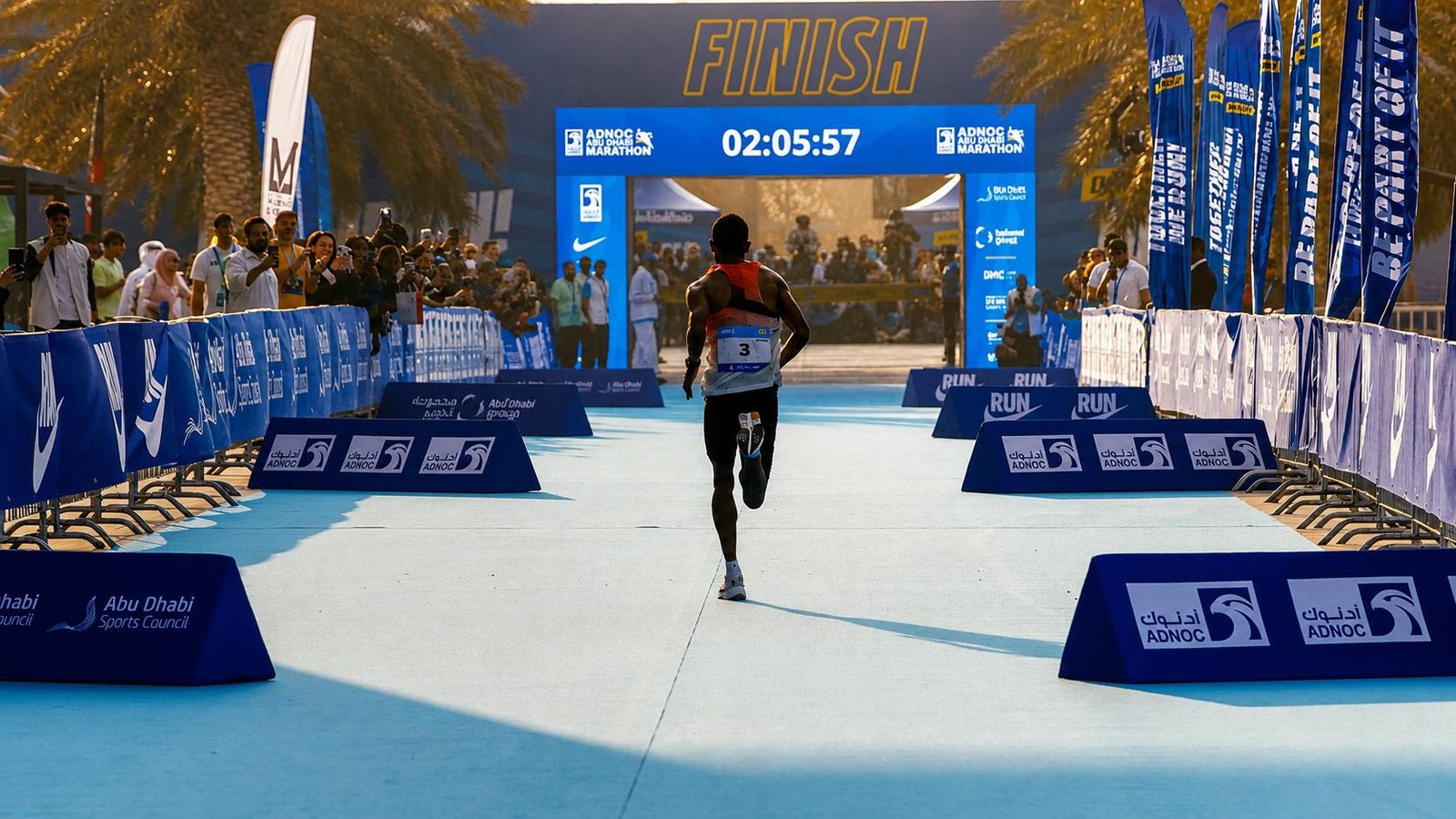 Elite runner approaching the finish line at the Abu Dhabi Marathon with spectators and official race branding.
