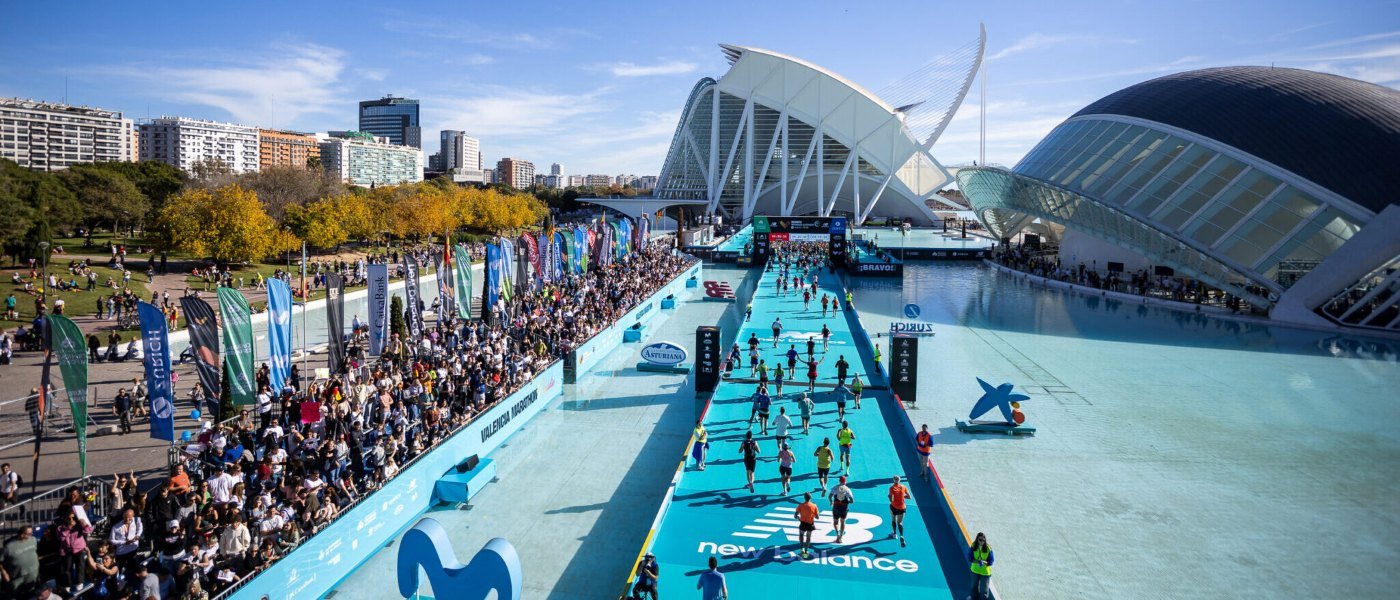 Runners crossing the iconic blue runway finish line at the Valencia Marathon Trinidad Alfonso Zurich, with the City of Arts and Sciences in the background