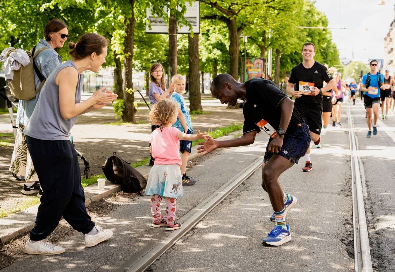 Runners racing through Stockholm city streets at the adidas Stockholm Marathon with the 1912 Olympic Stadium in the background