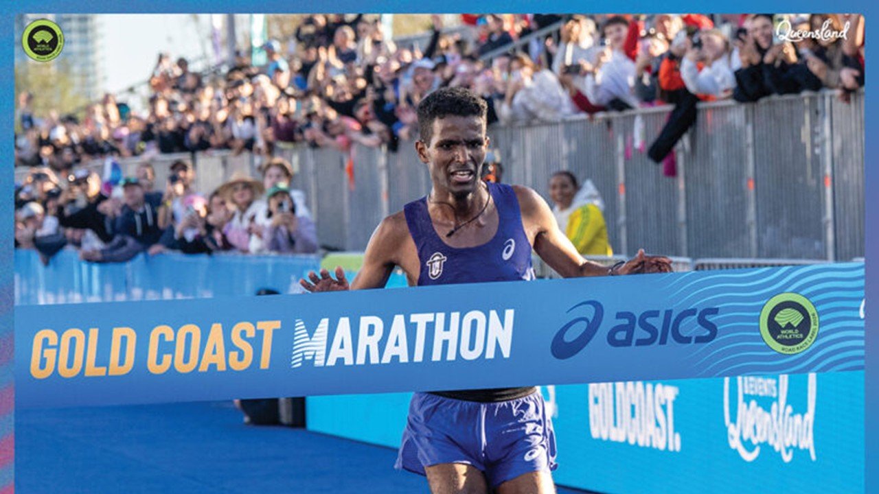 Australian runner Haftu Strintzos smiling and crossing the finish line tape to win the 2026 ASICS Gold Coast Marathon.