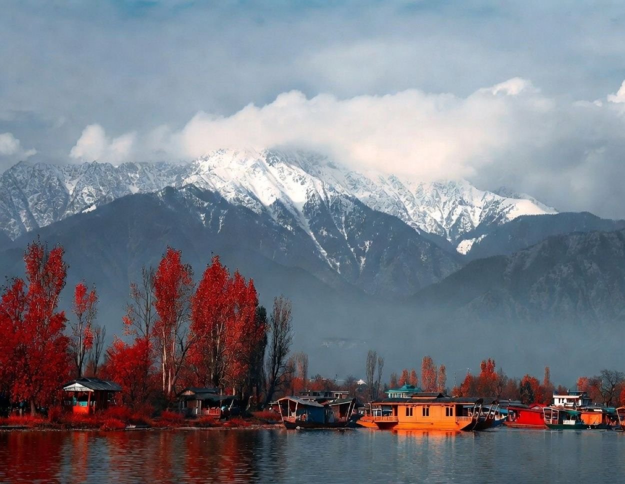 Scenic autumn view of Dal Lake in Srinagar with houseboats, vibrant Chinar trees, and Himalayan mountains — backdrop for Kashmir Marathon 2026 on 25 October