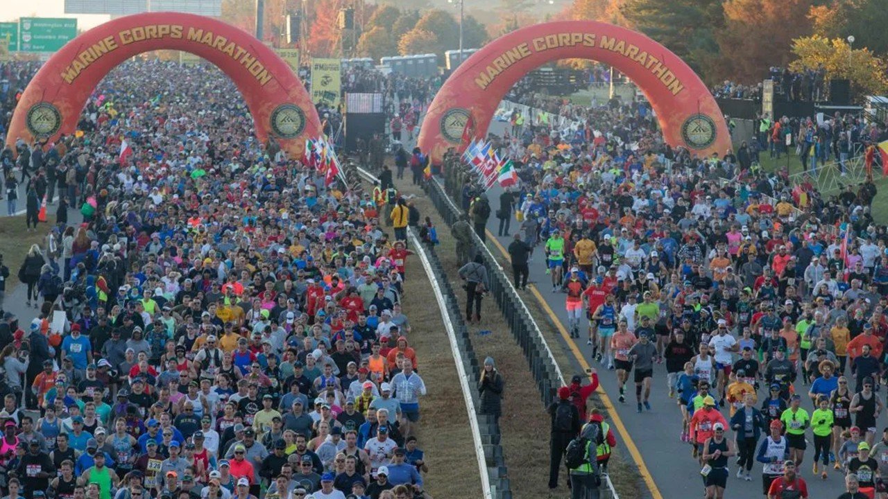 Thousands of runners crossing the start line under the Marine Corps Marathon arch at the 51st Marine Corps Marathon 2026 in Arlington Virginia