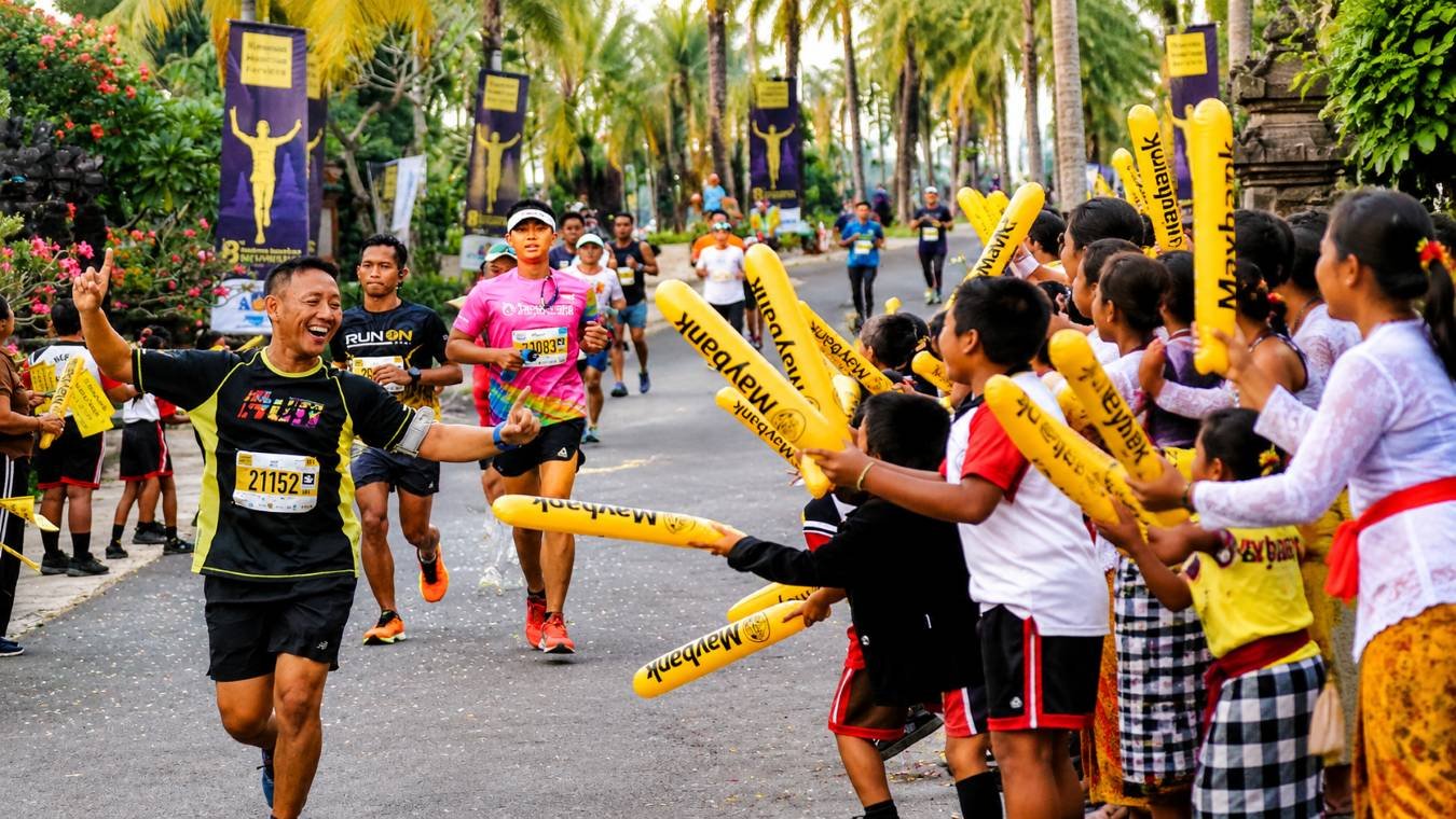 Runners pass enthusiastic spectators in traditional Balinese attire during the Maybank Bali Marathon.