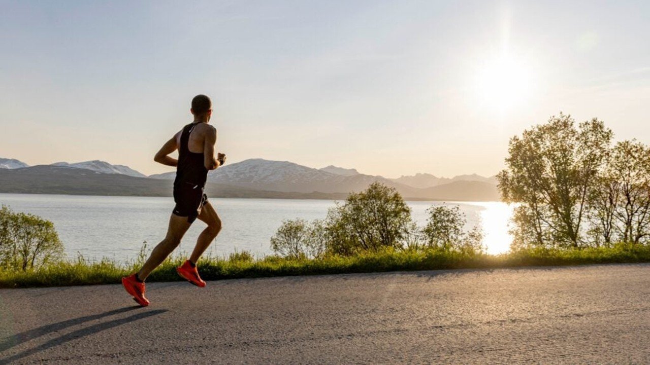 Runner crossing Tromsøbrua bridge during the Midnight Sun Marathon in Tromsø, Norway, with Arctic mountains in the background