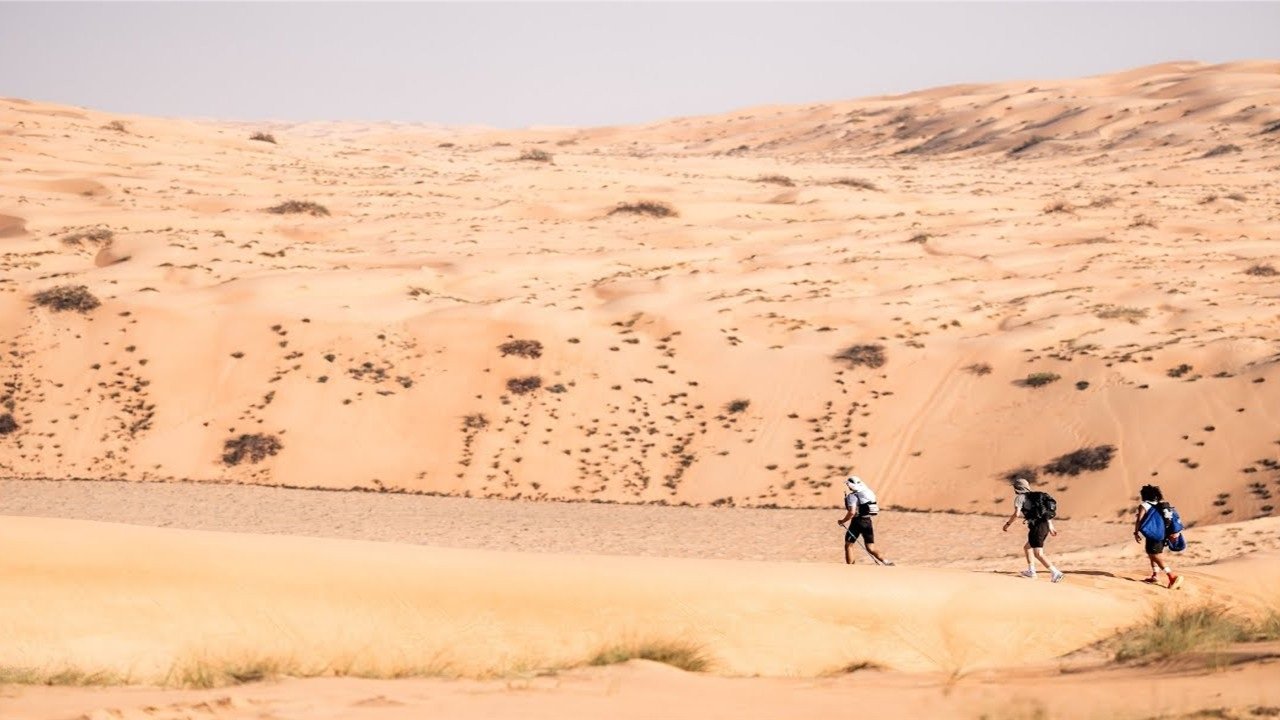 Runners crossing golden sand dunes at the Oman Desert Marathon in the Wahiba Sands, Oman