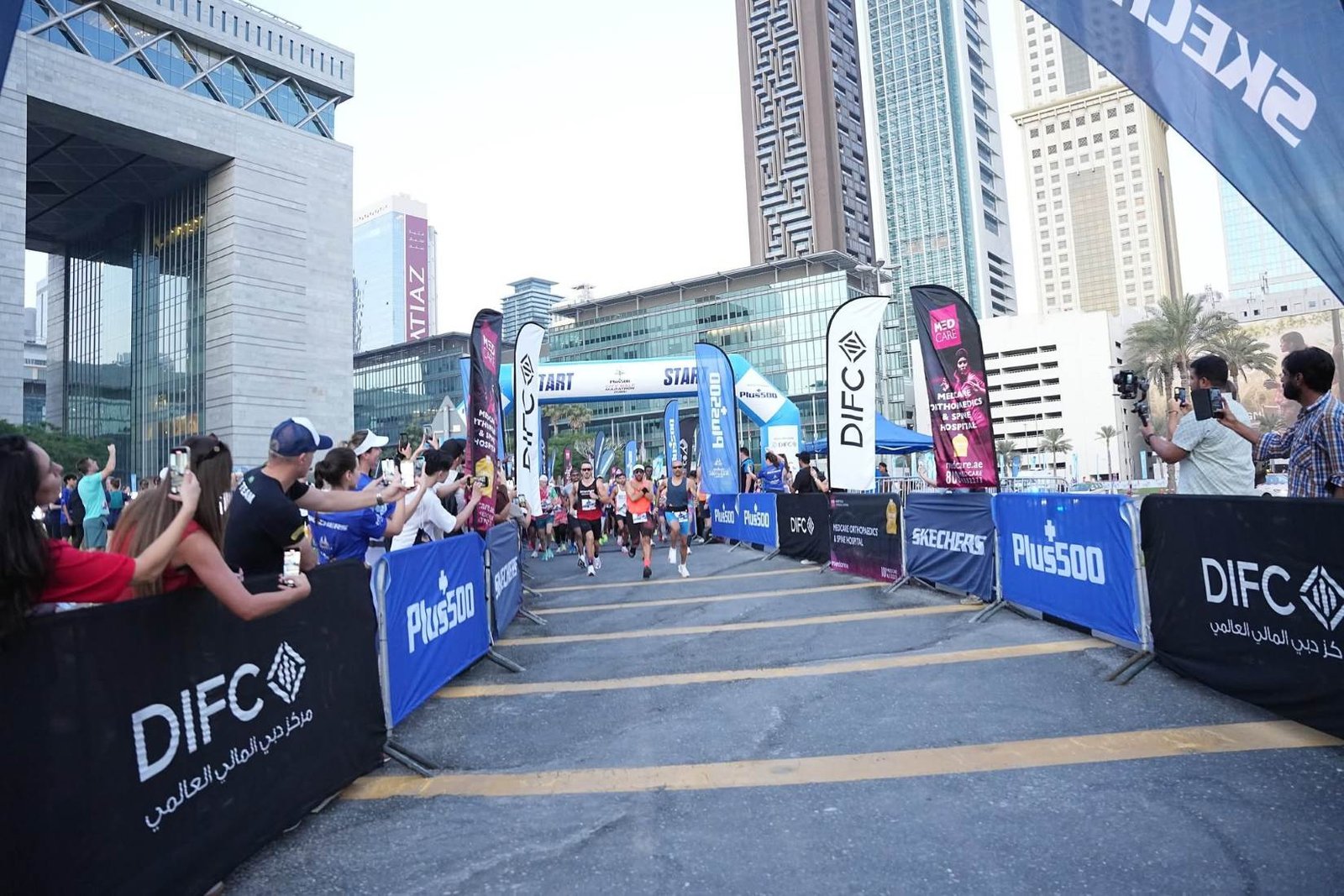 Runners at the Plus500 City Half Marathon Dubai 2026 DIFC Gate Building.