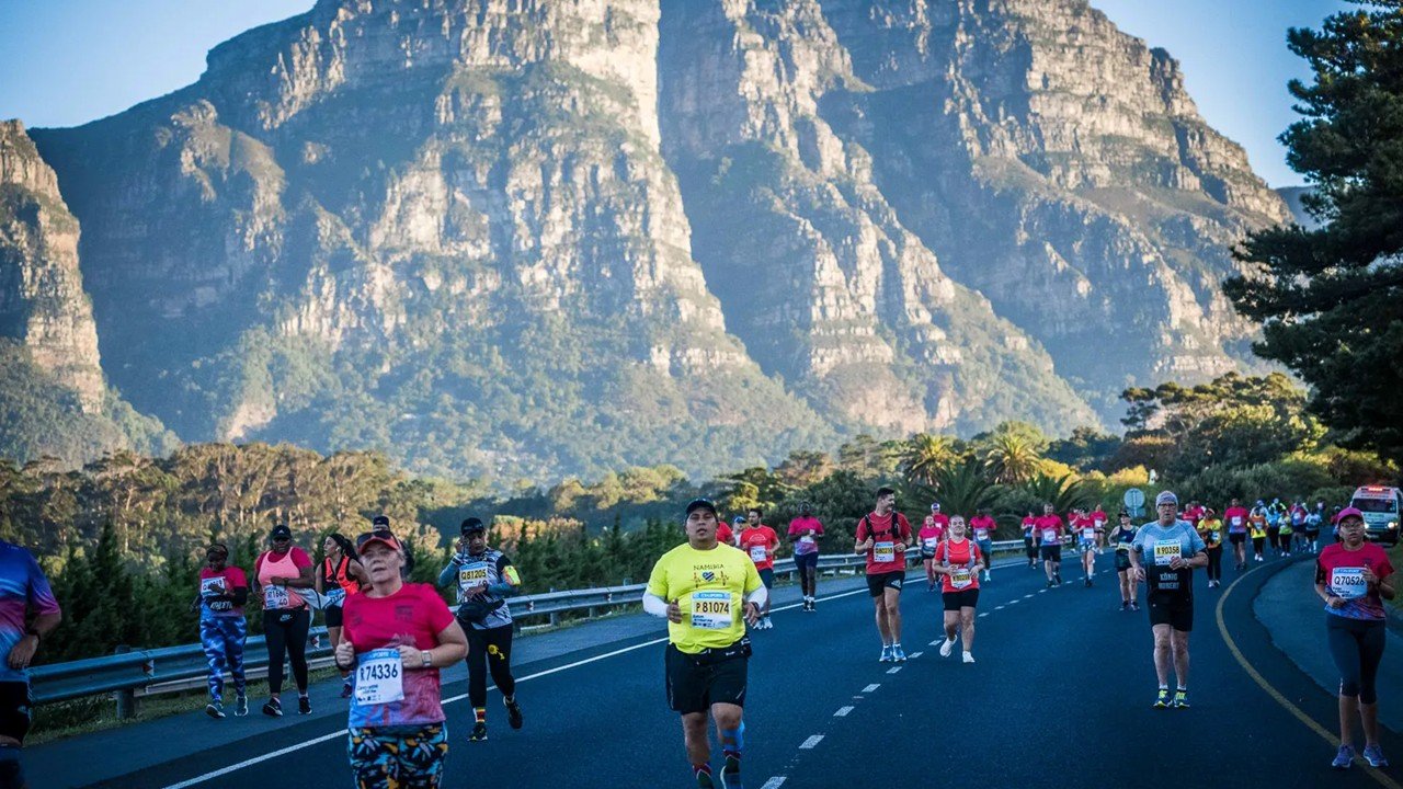 Runners participating in the Two Oceans Ultra Marathon with the iconic Cape Town mountains rising in the background.