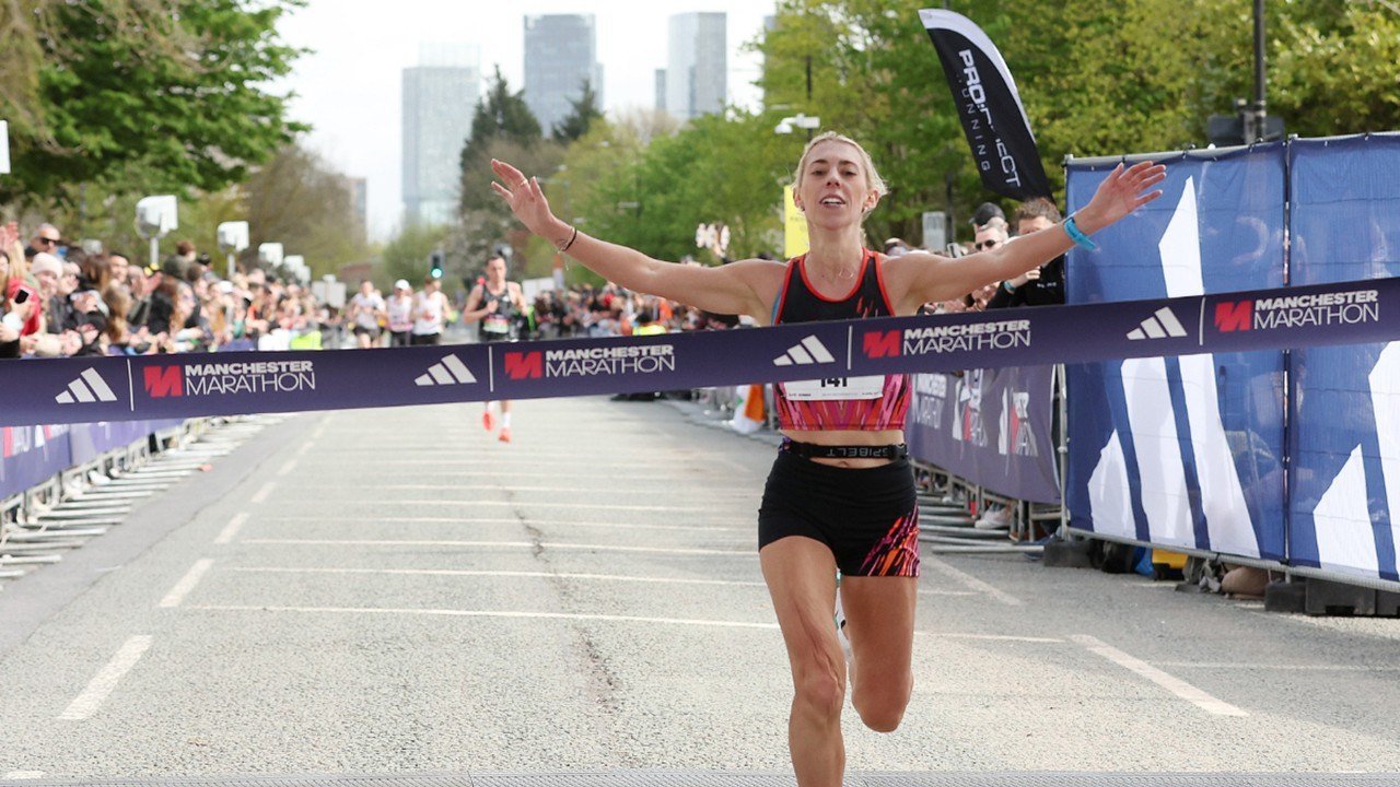 adidas Manchester Marathon runner crossing the finish line on Oxford Road, Manchester