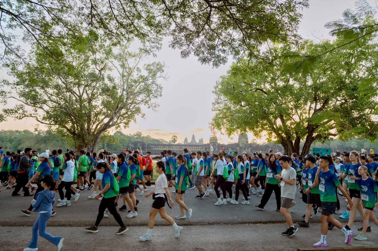 Runners at the start line of the Angkor Wat International Half Marathon with the ancient temple silhouetted at dawn