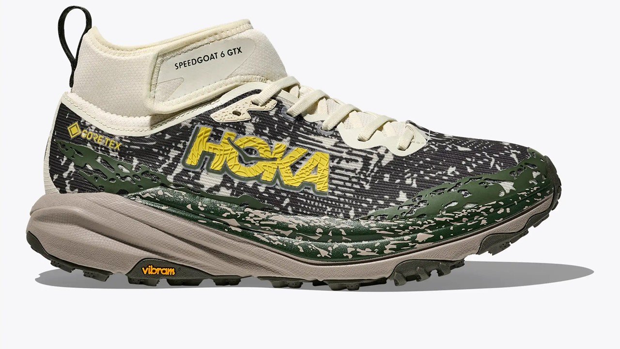 HOKA Speedgoat 6 Mid GTX trail shoe lateral view showing mid-cut GORE-TEX collar, Vibram Megagrip outsole lugs and terrain-print upper with yellow HOKA branding