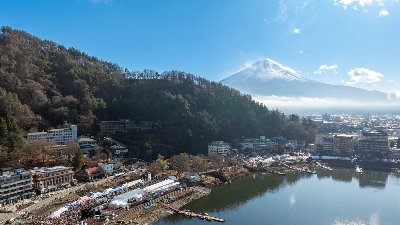 Runners racing along Lake Kawaguchiko with snow-capped Mount Fuji in the background at the Mt. Fuji International Marathon.