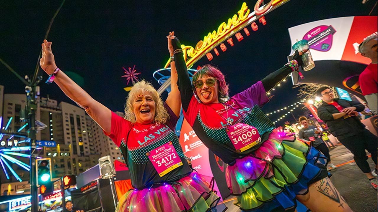 Runners on a closed Las Vegas Strip at night during the Rock 'n' Roll Las Vegas half marathon with neon lights and casino facades lit up in the background