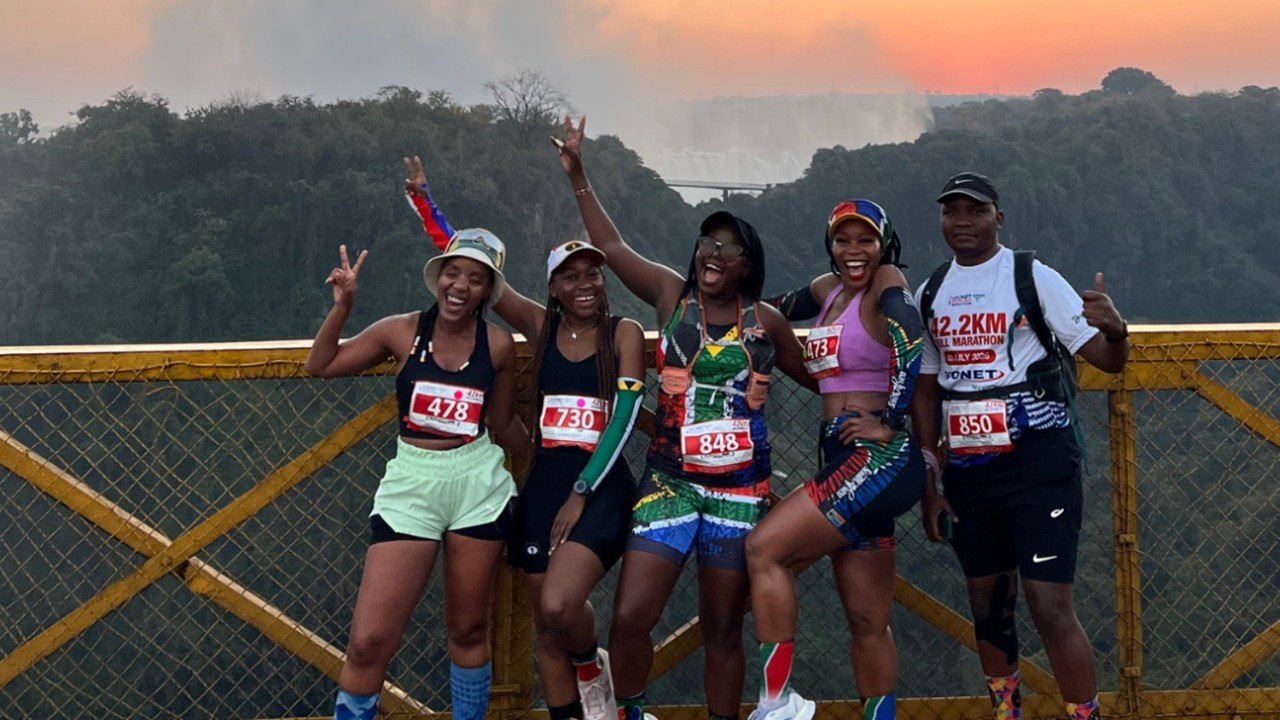 Runners posing for a group photo at the Econet Victoria Falls Marathon with the Zambezi gorge and African landscape in the background
