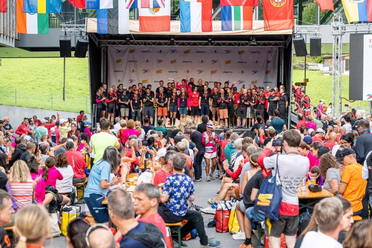 Prize ceremony at the 33rd Jungfrau-Marathon 2026, with athletes on stage beneath a row of international flags at Eigergletscher