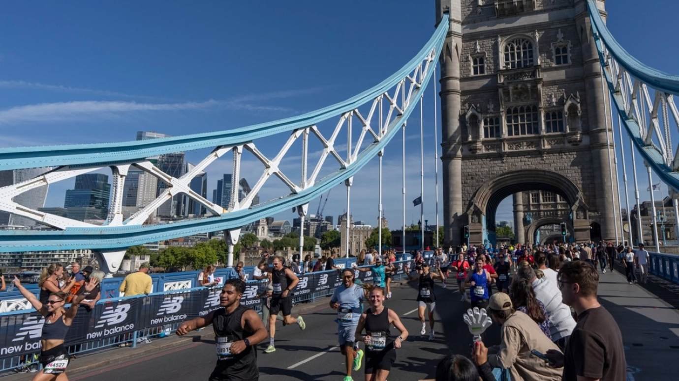 Runners crossing Tower Bridge during the London Big Half Marathon, with New Balance race barriers, cheering spectators and the City of London skyline in the background