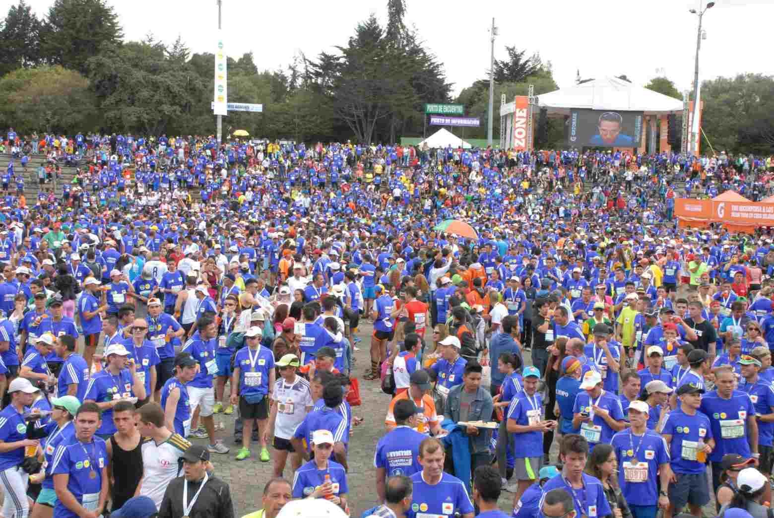 Thousands of runners gather at Simón Bolívar Park after finishing the Bogotá Half Marathon, wearing official blue race shirts and finisher medals