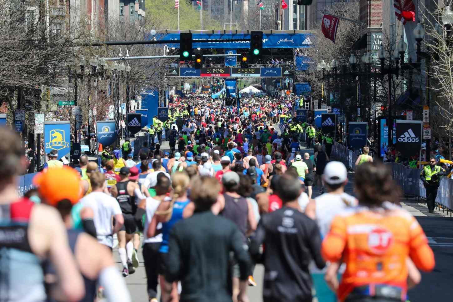 Runners approaching the Boston Marathon finish line on Boylston Street with the B.A.A. timing gantry overhead