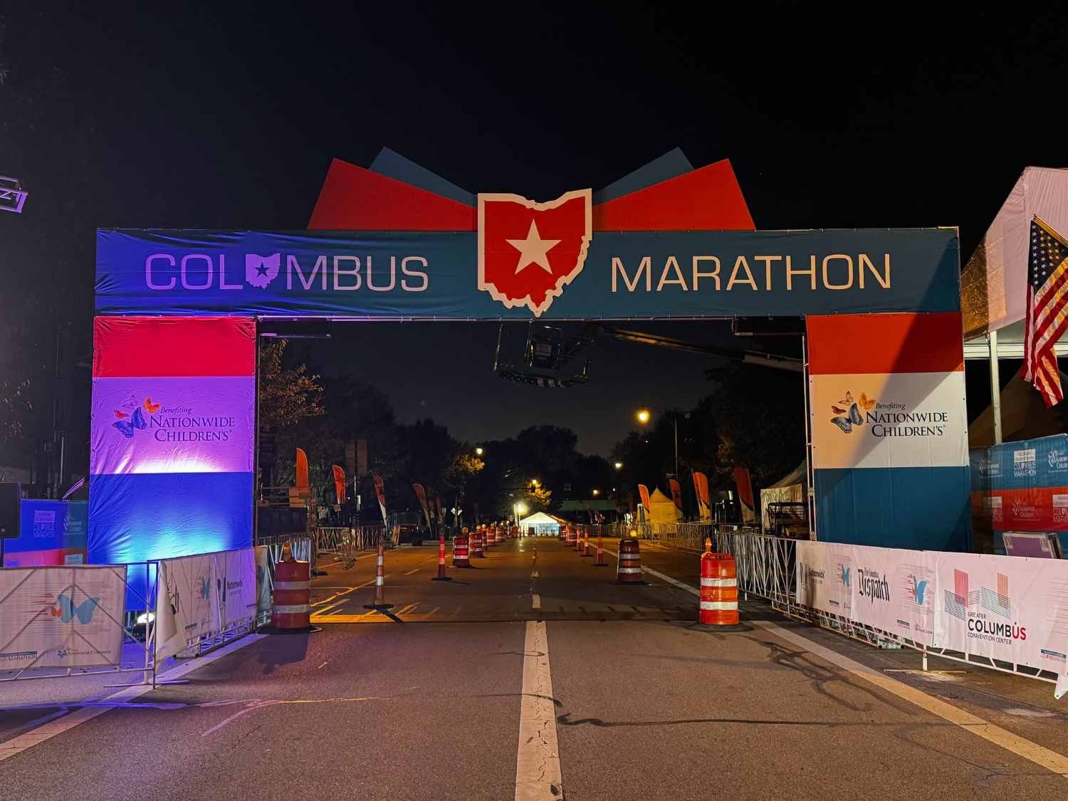 The Columbus Marathon start arch lit up at night, with the Ohio state outline and star logo, benefiting Nationwide Children’s Hospital