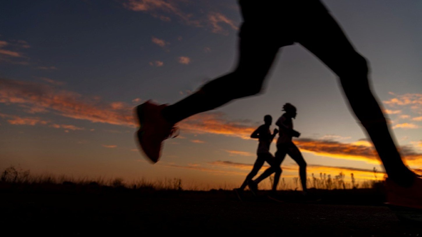 Runners in silhouette against a golden sunset sky during the Comrades Marathon in South Africa