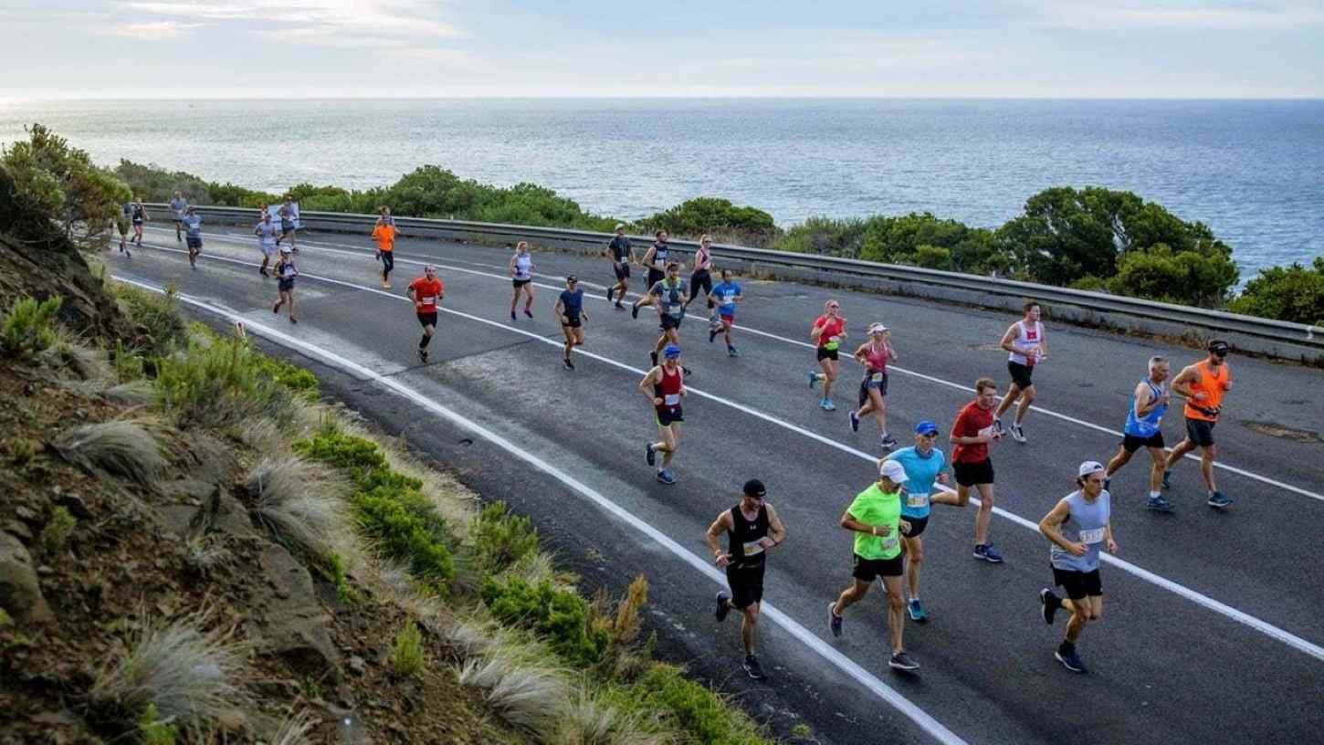 Runners on the Great Ocean Road Marathon course with the Southern Ocean visible below the coastal cliffs
