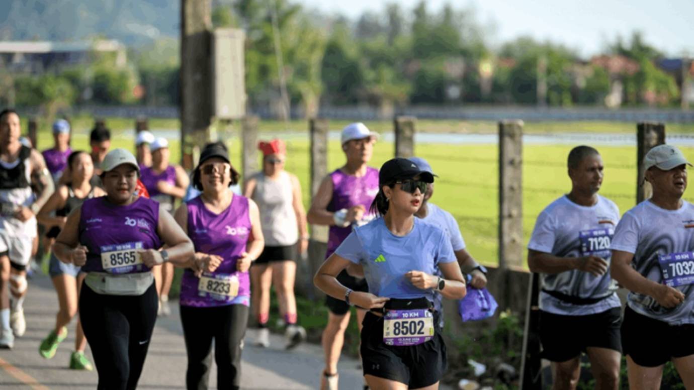 Runners competing in the 10km category at the Laguna Phuket Marathon, passing through the rural Thalang district road with rice paddies in the background