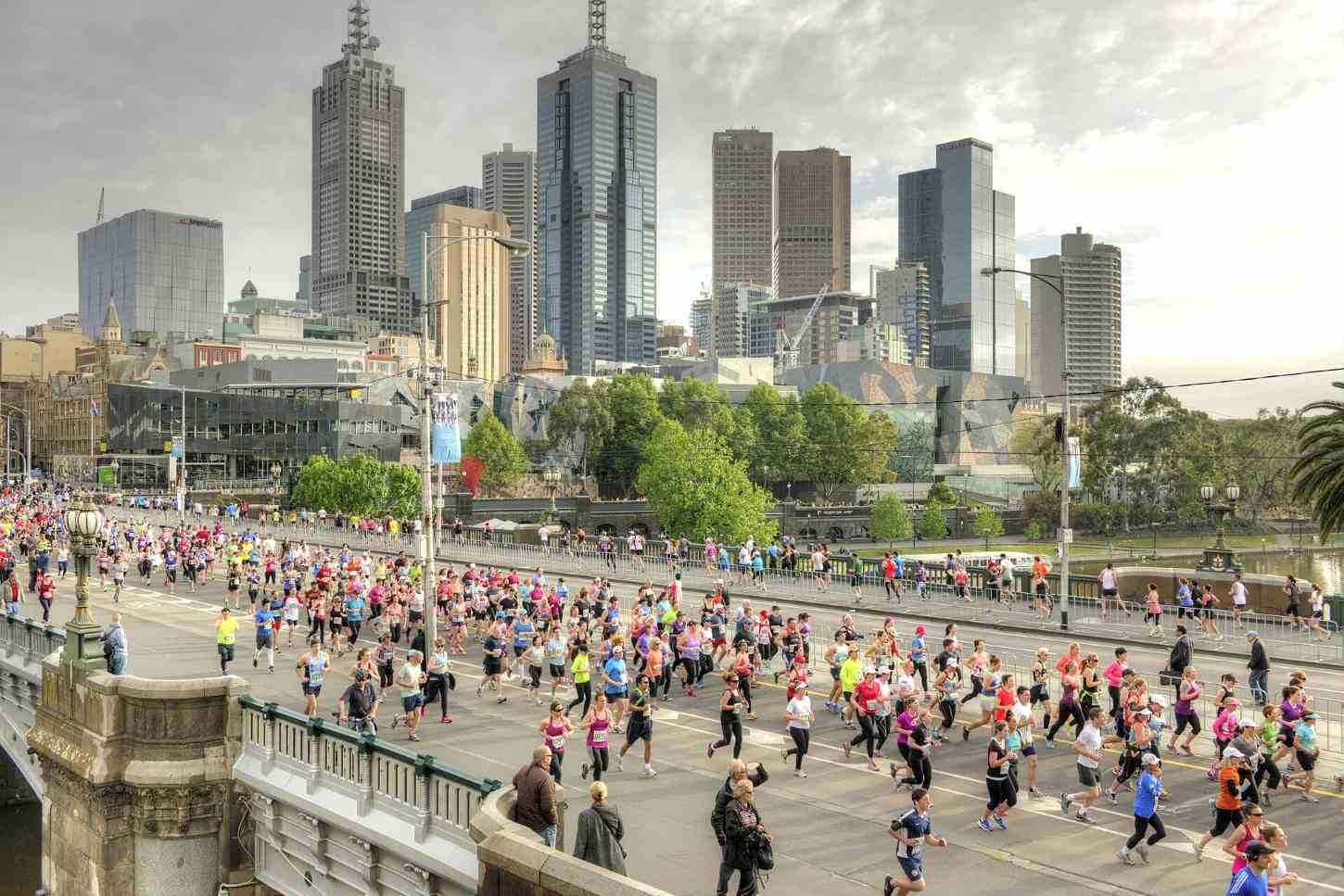 Thousands of runners crossing Princes Bridge during the Melbourne Marathon, with the Melbourne CBD skyline in the background