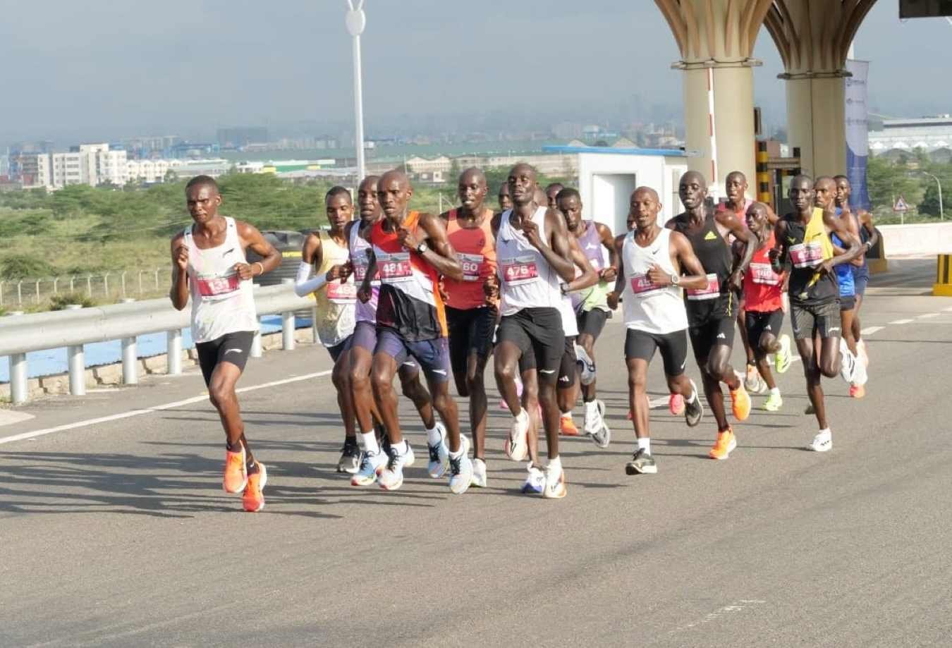 Elite runners in the lead pack on the Nairobi Expressway during the Nairobi City Marathon, with the city skyline visible in the background
