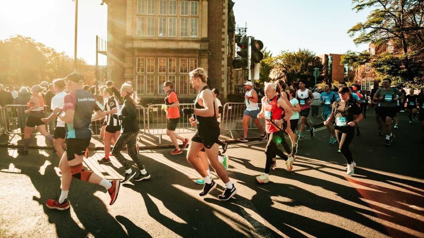 Runners setting off at the Oxford Half Marathon on a sunny October morning, passing historic university buildings on the closed-road course
