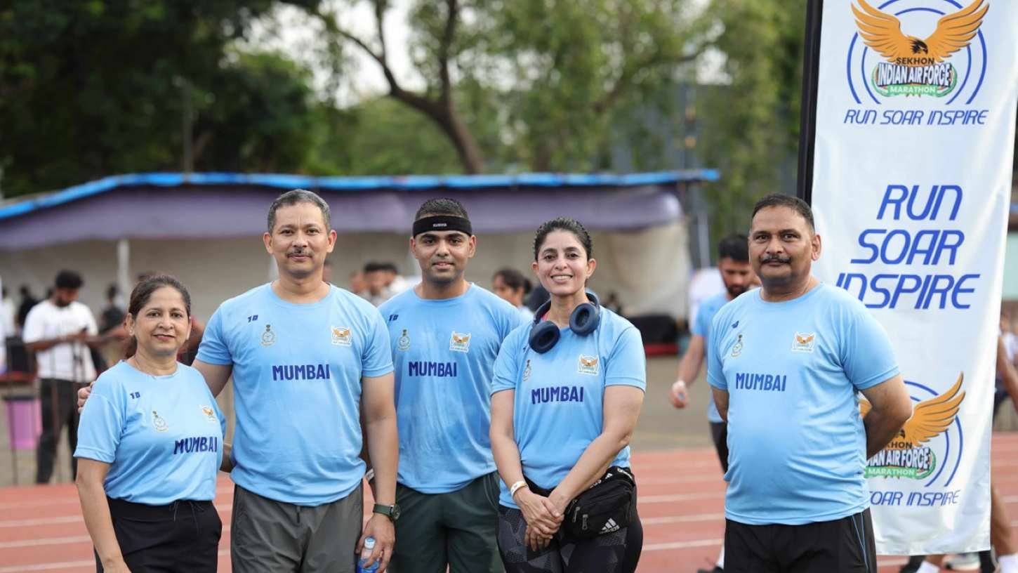 IAF personnel and participants in Mumbai-branded Sekhon Indian Air Force Marathon 2026 t-shirts at the race venue, with the Run Soar Inspire event banner behind them