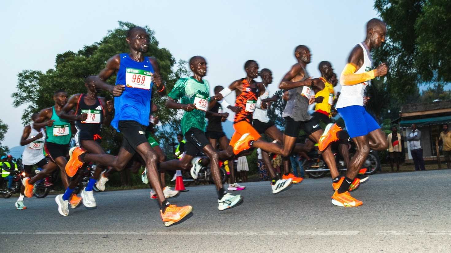Runners on the Tusker Lite Rwenzori Marathon course with the Rwenzori Mountains in the background, Kasese, Uganda